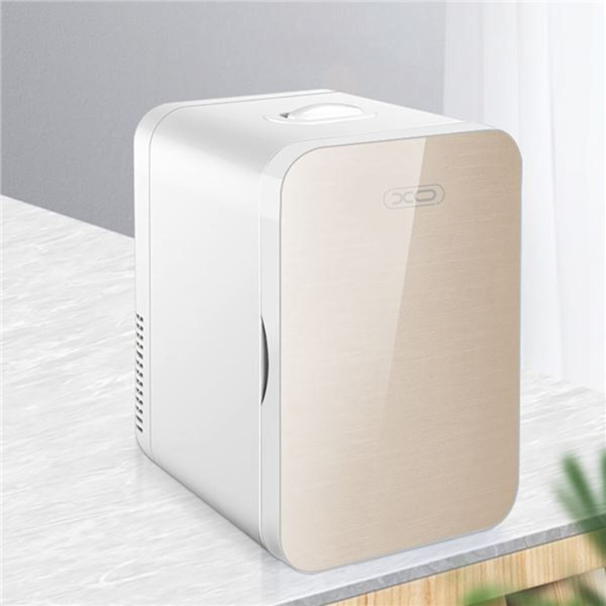 Un mini refrigerador compacto blanco y dorado sobre una superficie de mármol.