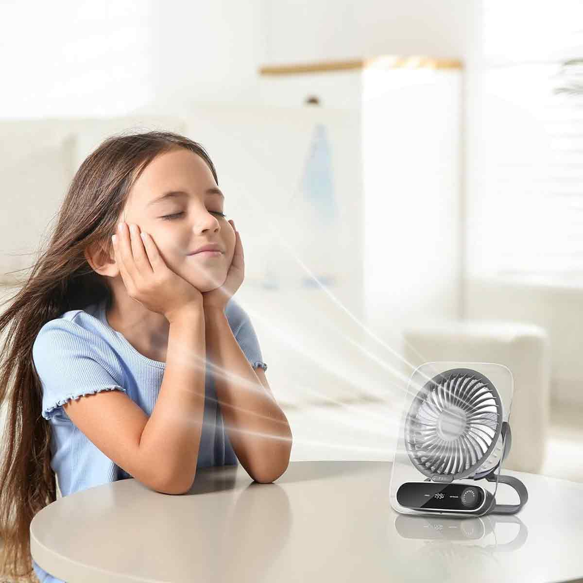 Ein Mädchen genießt den Luftstrom eines kleinen Ventilators.