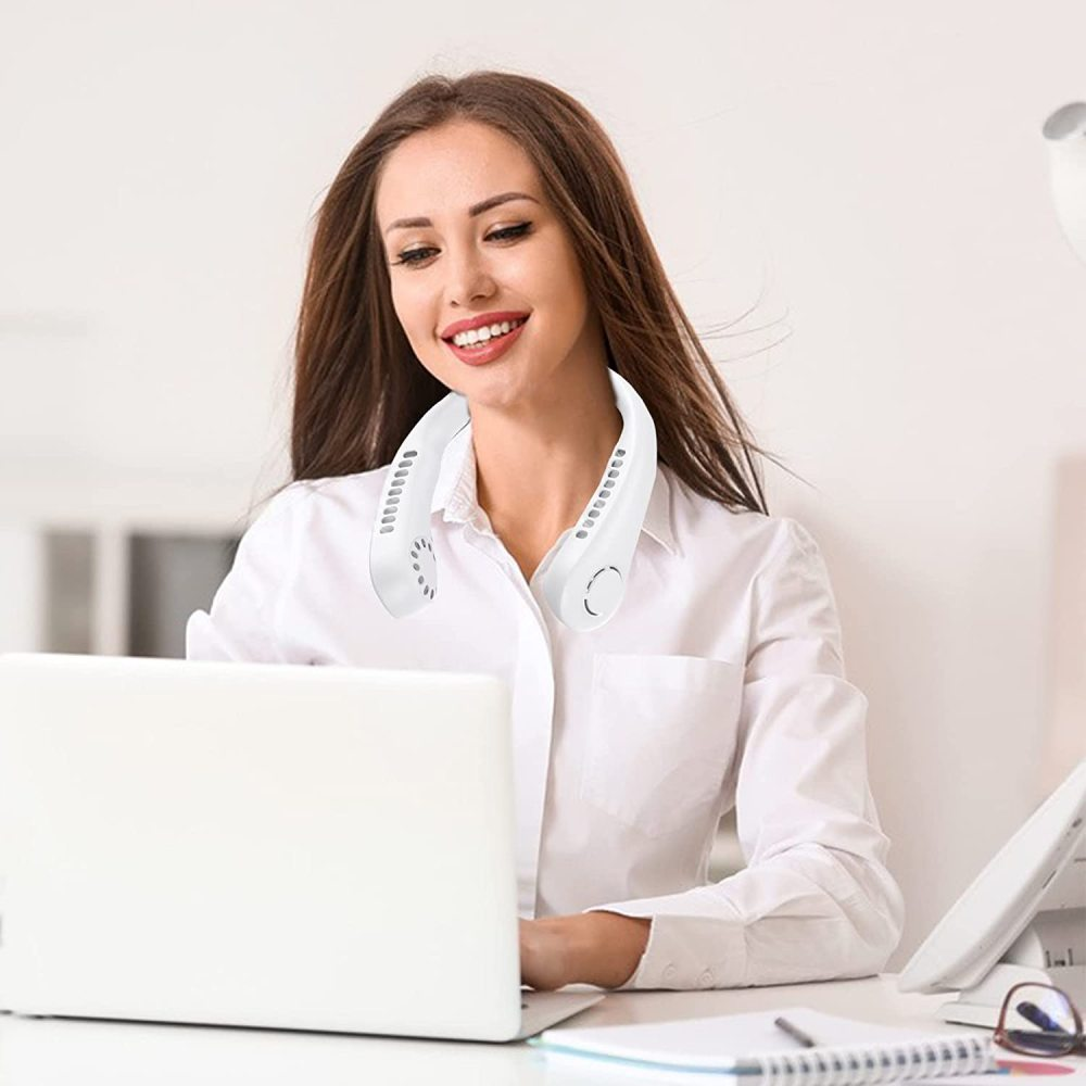 Eine Frau mit einem weißen Nackenventilator sitzt an einem Schreibtisch und benutzt einen Laptop.