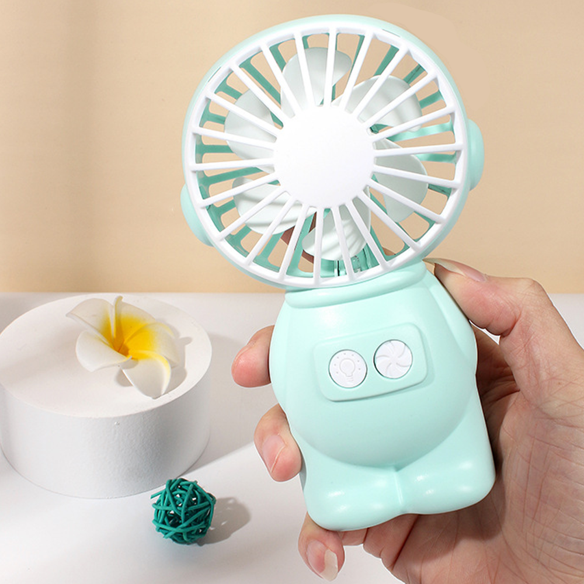 Eine Person hält einen hellgrünen Mini-Ventilator mit weißem Gitter und Rotorblättern.