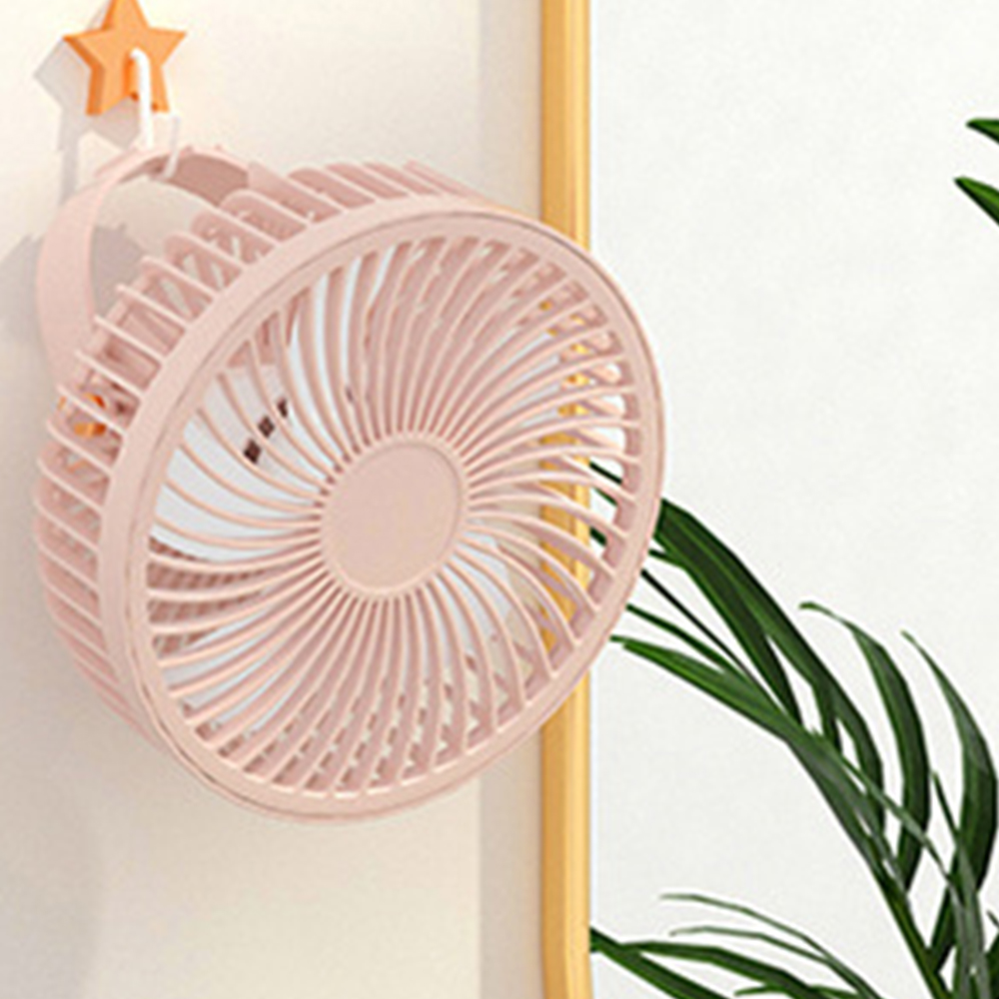 Ein rosafarbener Ventilator hängt an einer Wand mit einem orangefarbenen Sternhaken.