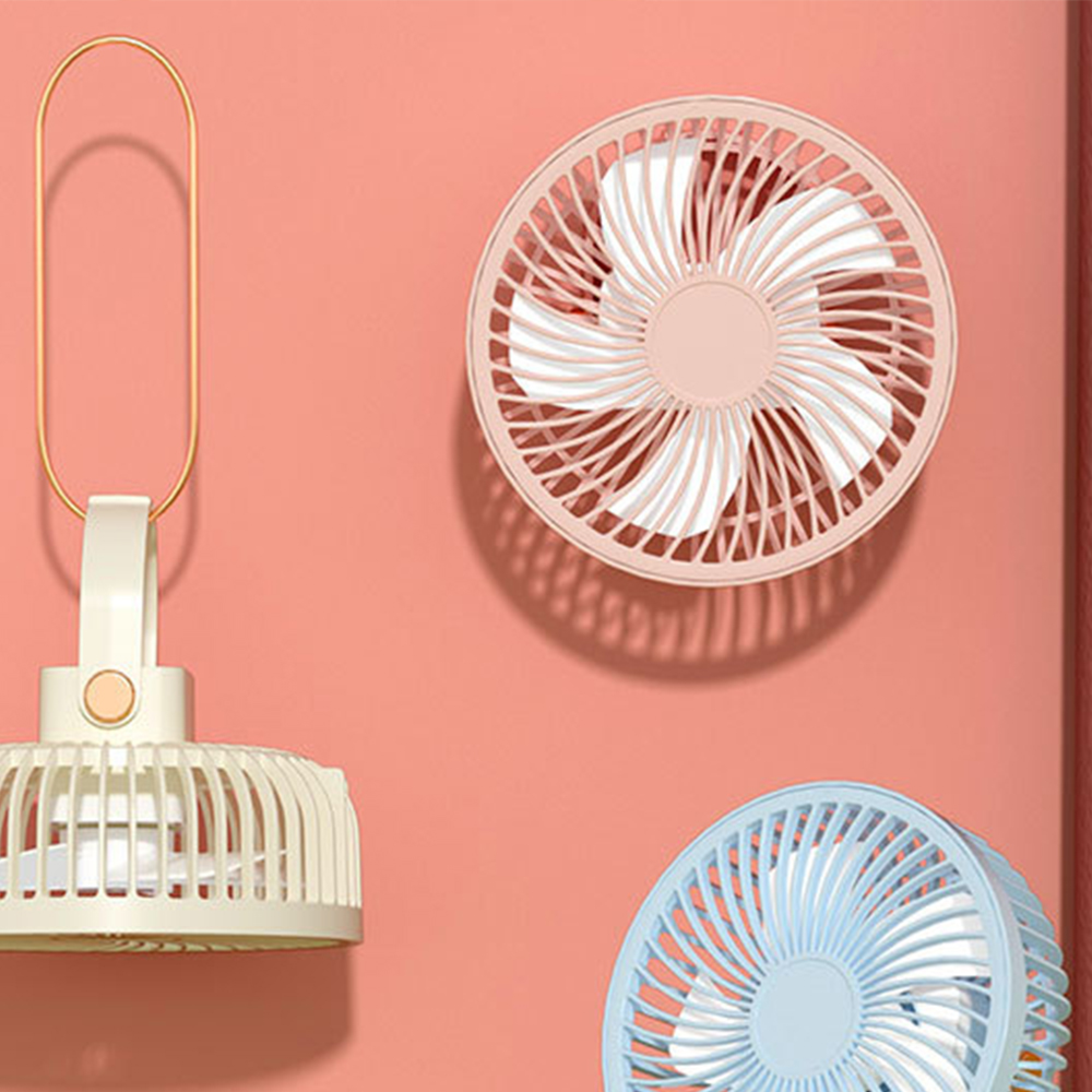 Drei Ventilatoren: ein weier, ein rosafarbener und ein blauer, an einer korallfarbenen Wand.