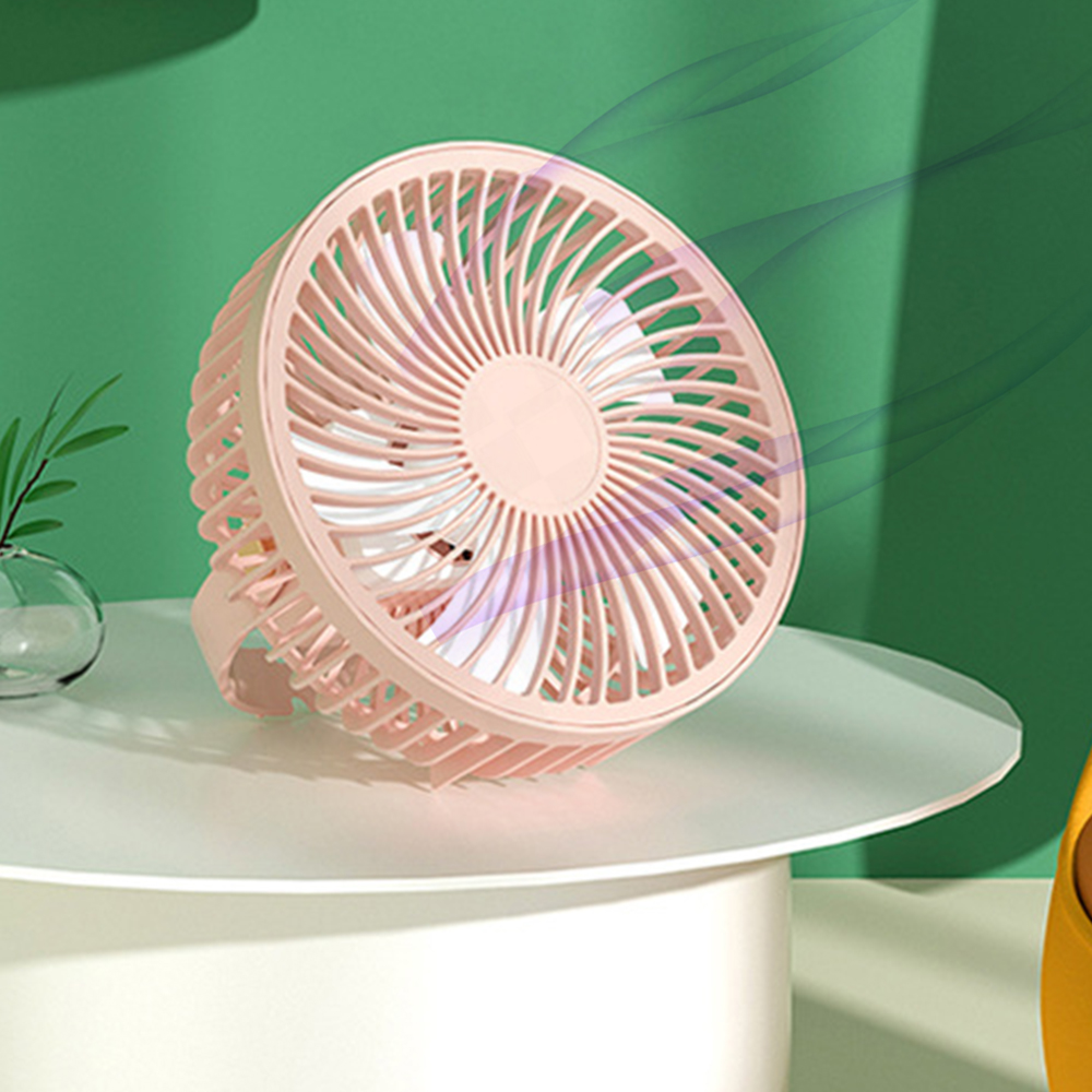 Ein kleiner rosa Ventilator steht auf einem weißen Tisch vor einem grünen Hintergrund.