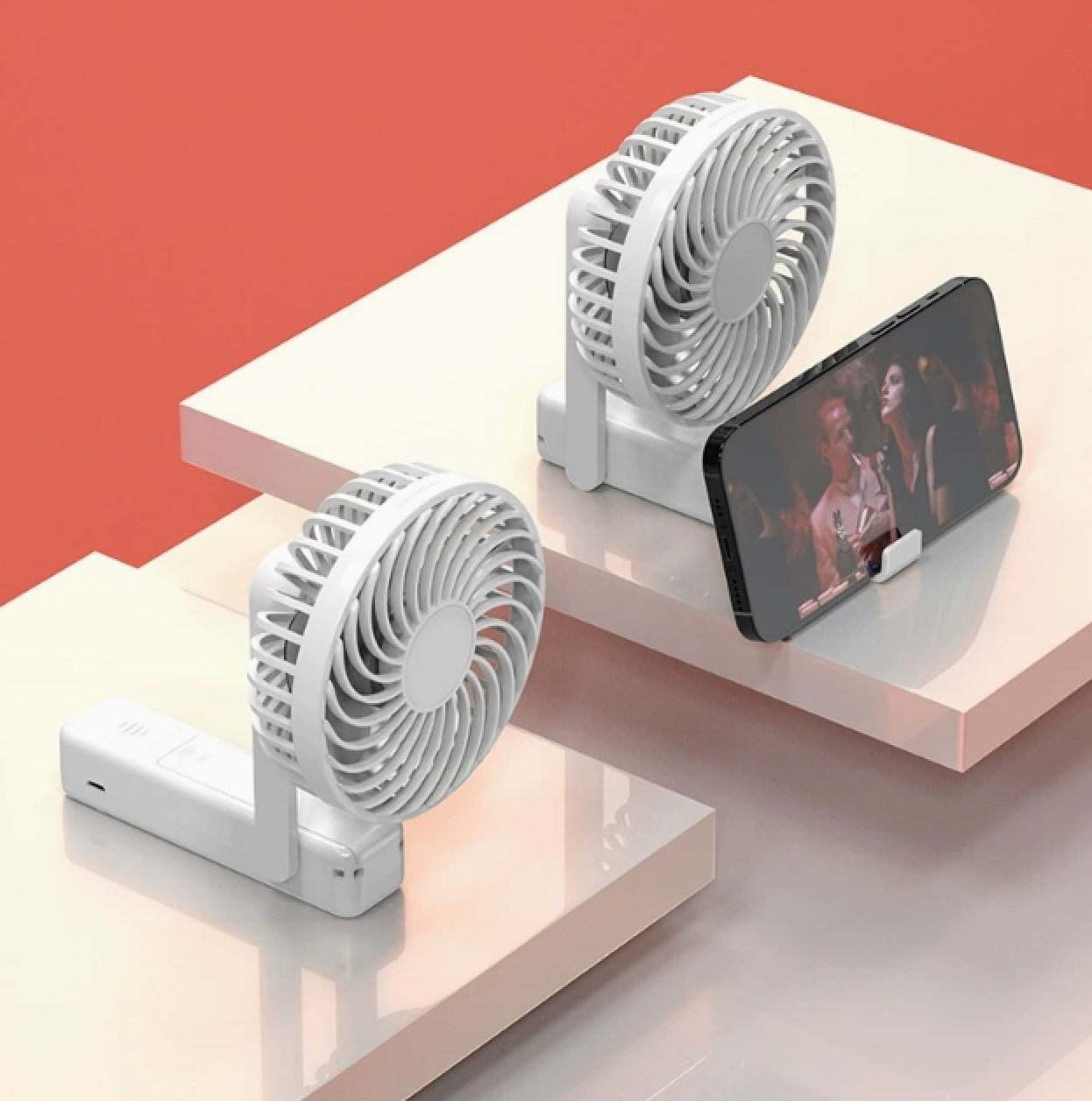 Zwei weiße tragbare Ventilatoren auf einer rosa und weißen gestuften Oberfläche. Ein Ventilator ist im Vordergrund.
