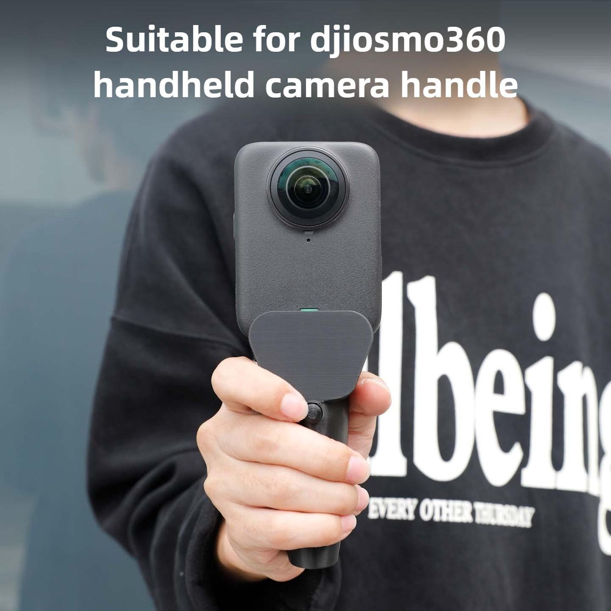 Persona che tiene una fotocamera 360 con manico. Felpa nera con testo.