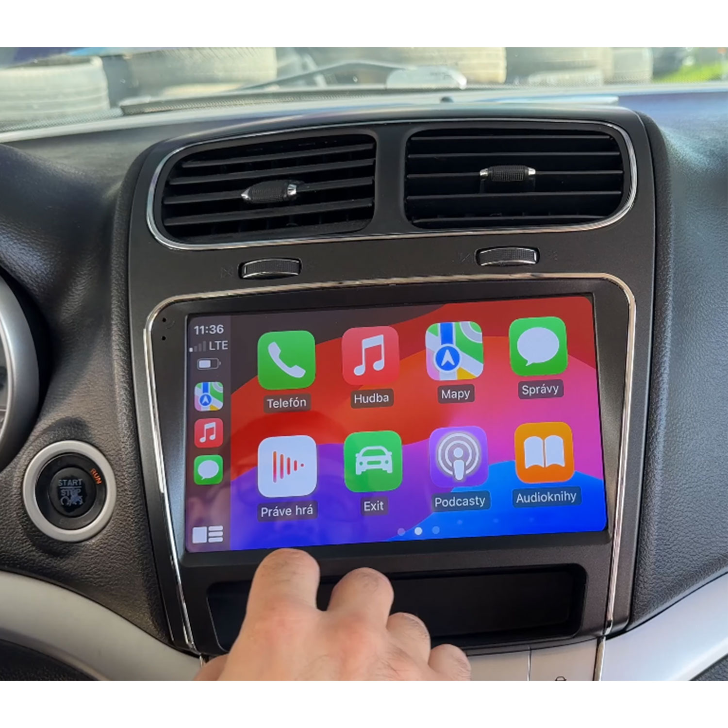 Ein Finger berührt den Touchscreen eines Autos mit Apple CarPlay-Menü.