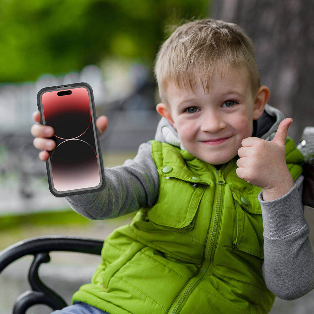 Bir çocuk dışarıda oturmuş telefon tutuyor, başparmak havada.