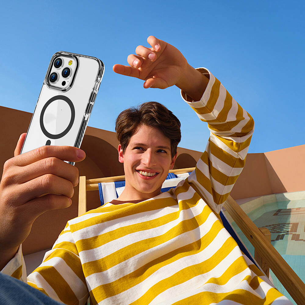 Sarı-beyaz çizgili kazaklı bir adam şeffaf kılıflı bir telefon tutuyor.
