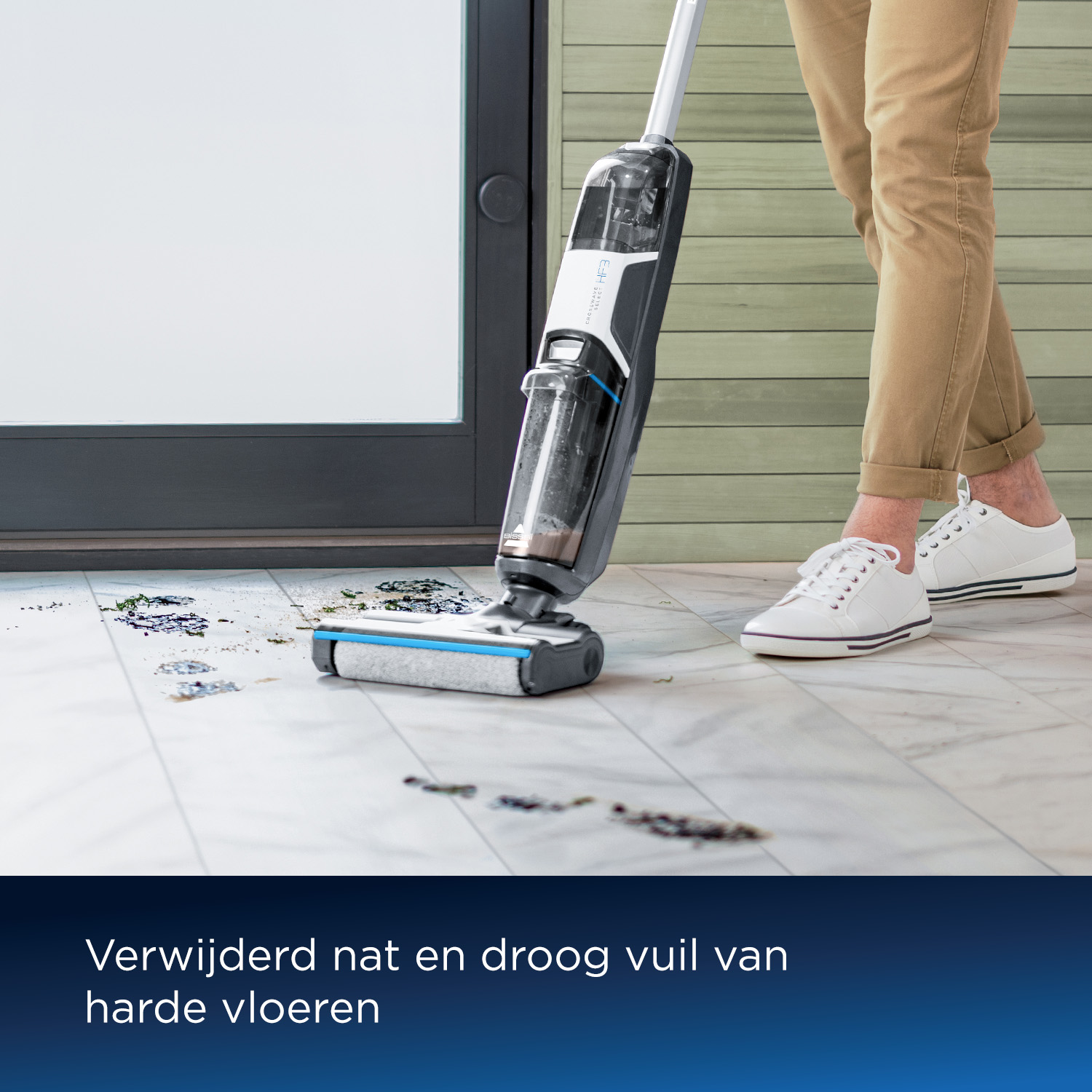 A person cleans a dirty floor with a wet/dry vacuum cleaner.