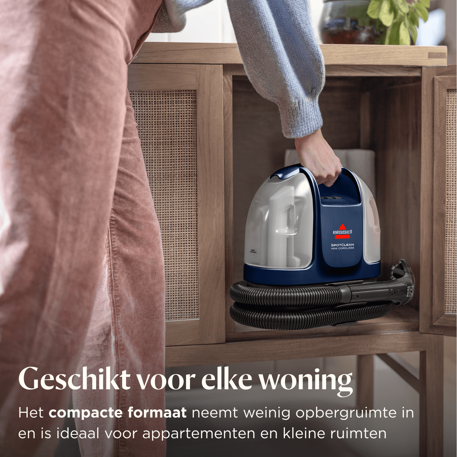 Una persona tiene un pulitore senza fili Bissell SpotClean Mini blu e bianco.