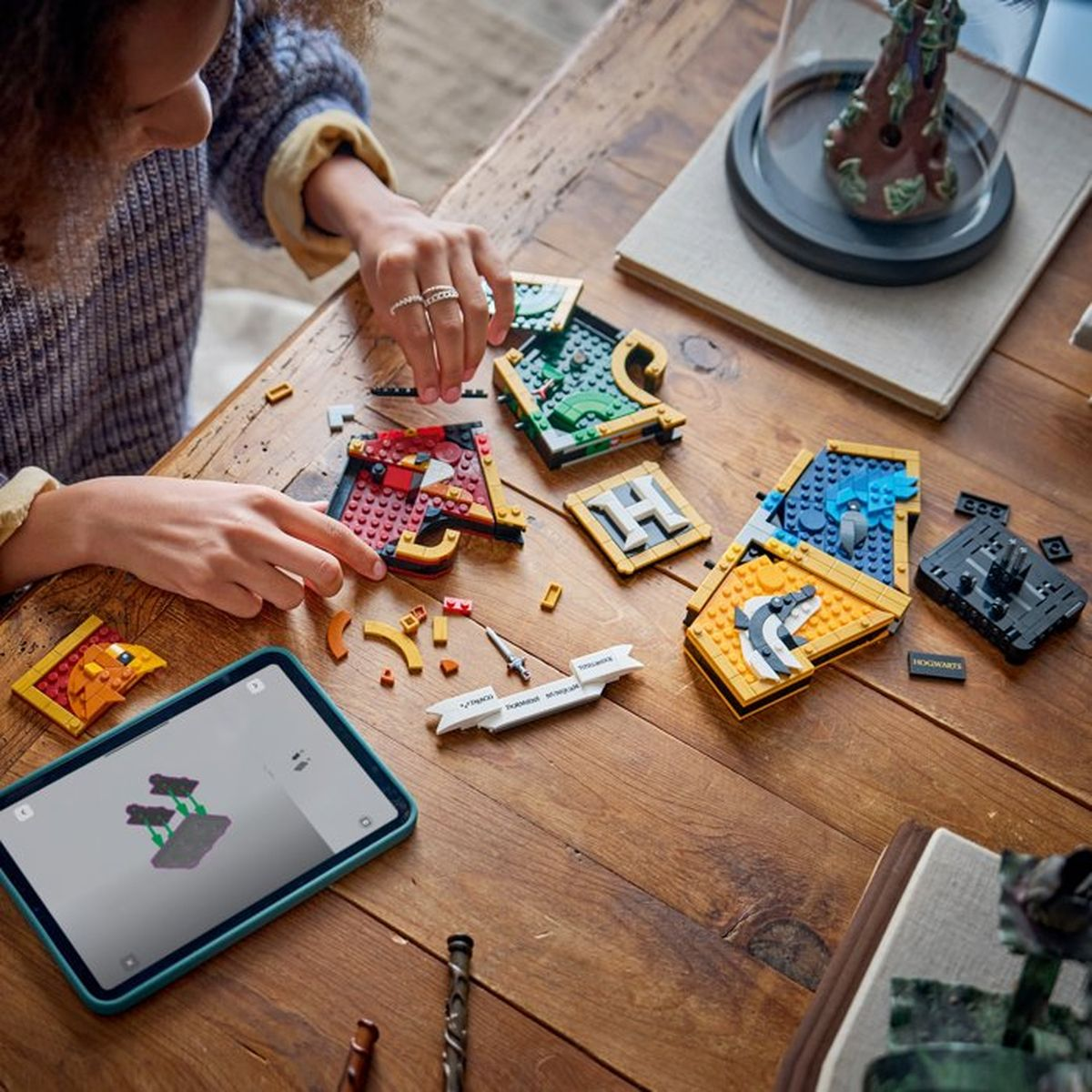 Persona che costruisce set Lego al tavolo, tablet con istruzioni nelle vicinanze.