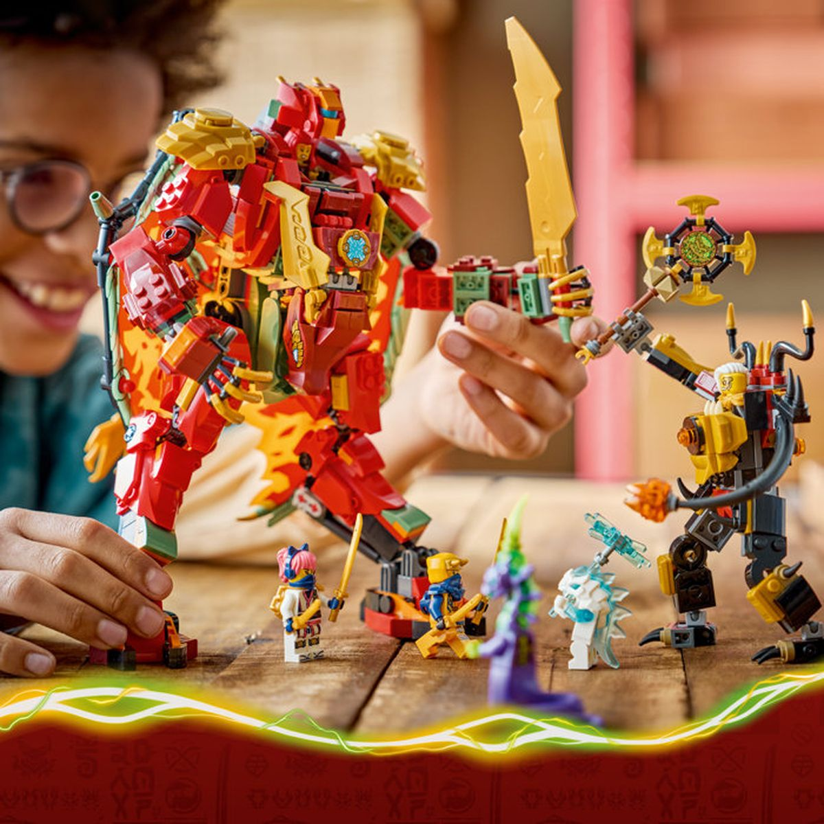 Un niño juega con robots Lego coloridos en una mesa de madera. Un gran robot rojo.