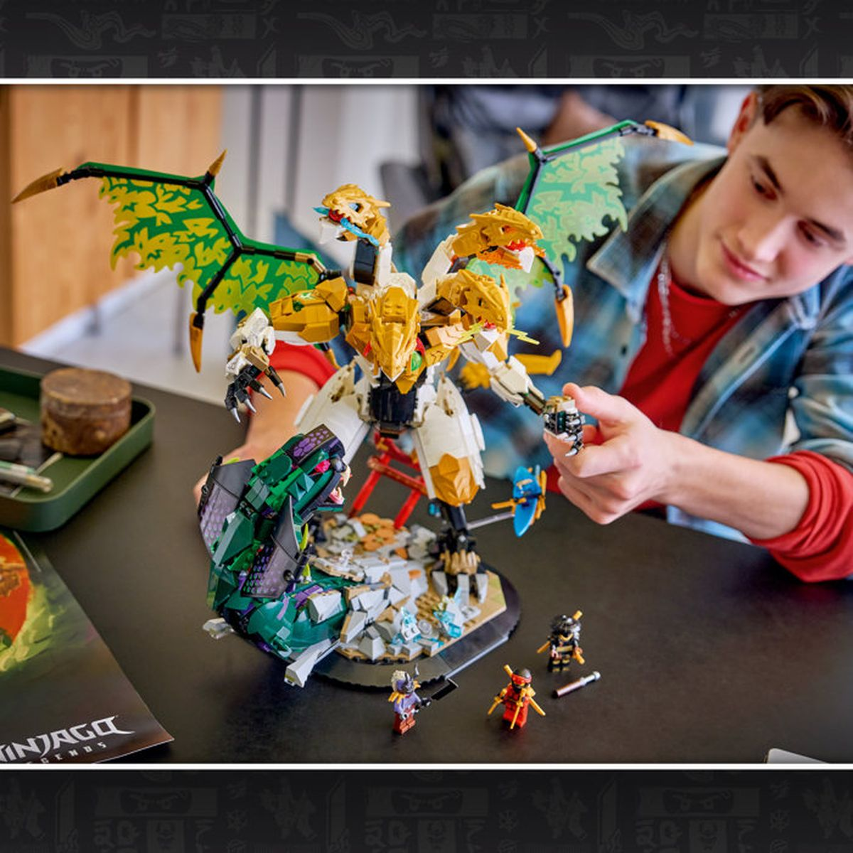 Ragazzo costruisce giocattolo drago Lego multi-testa con ali verdi.