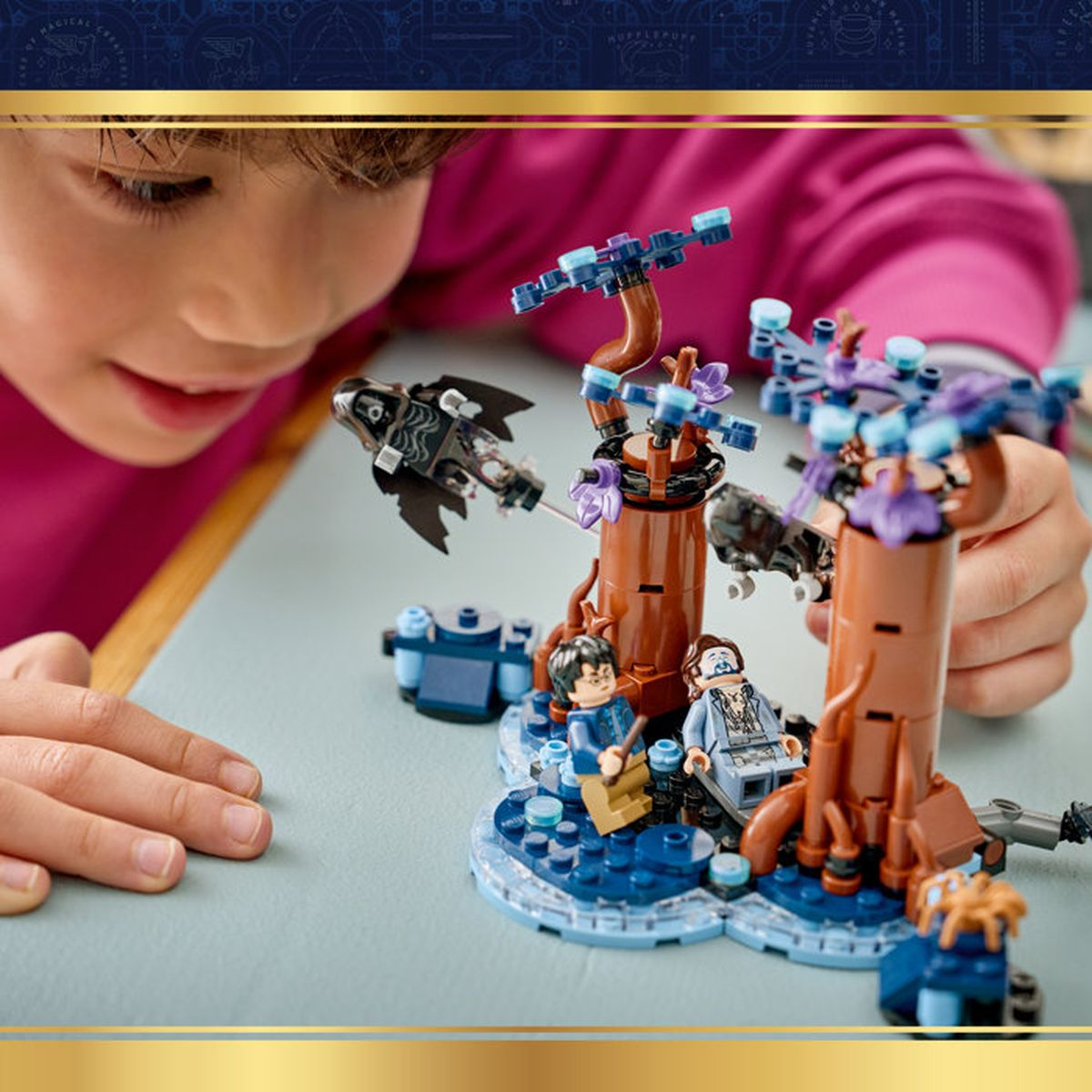 Un bambino gioca con un set LEGO Harry Potter con alberi e figure.