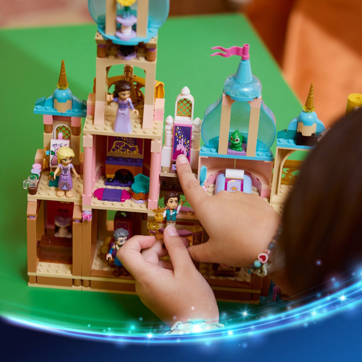 Dziecko bawi się kolorowym zamkiem z klocków Lego z postaciami i magicznymi elementami.