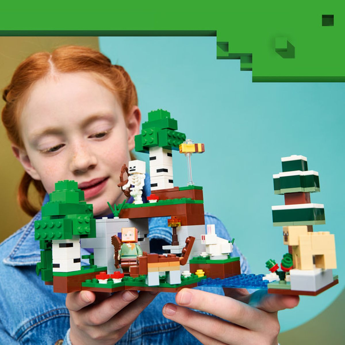 Una niña sostiene un set de LEGO de Minecraft con figuras, árboles y animales.