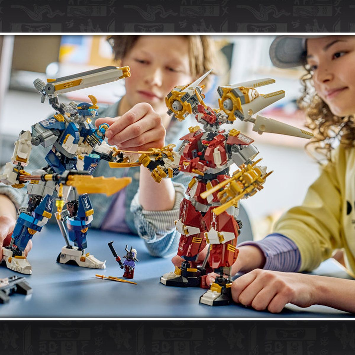 Niños construyen mechs de Lego: un mech azul y uno rojo sobre una mesa.