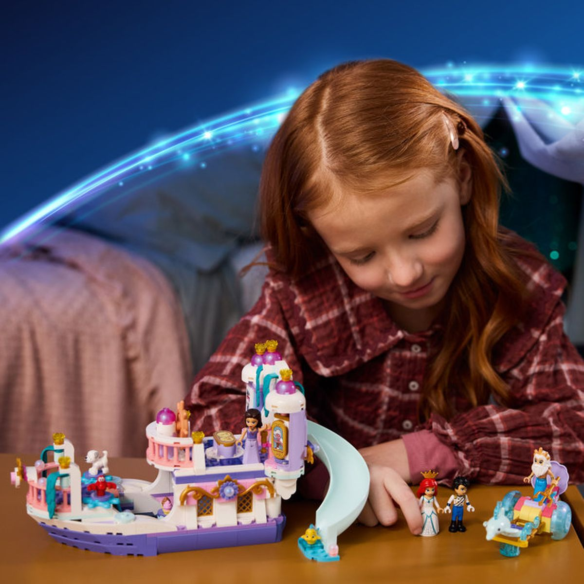 Dziewczynka bawi się zabawką-zamkiem Lego na statku z figurkami.