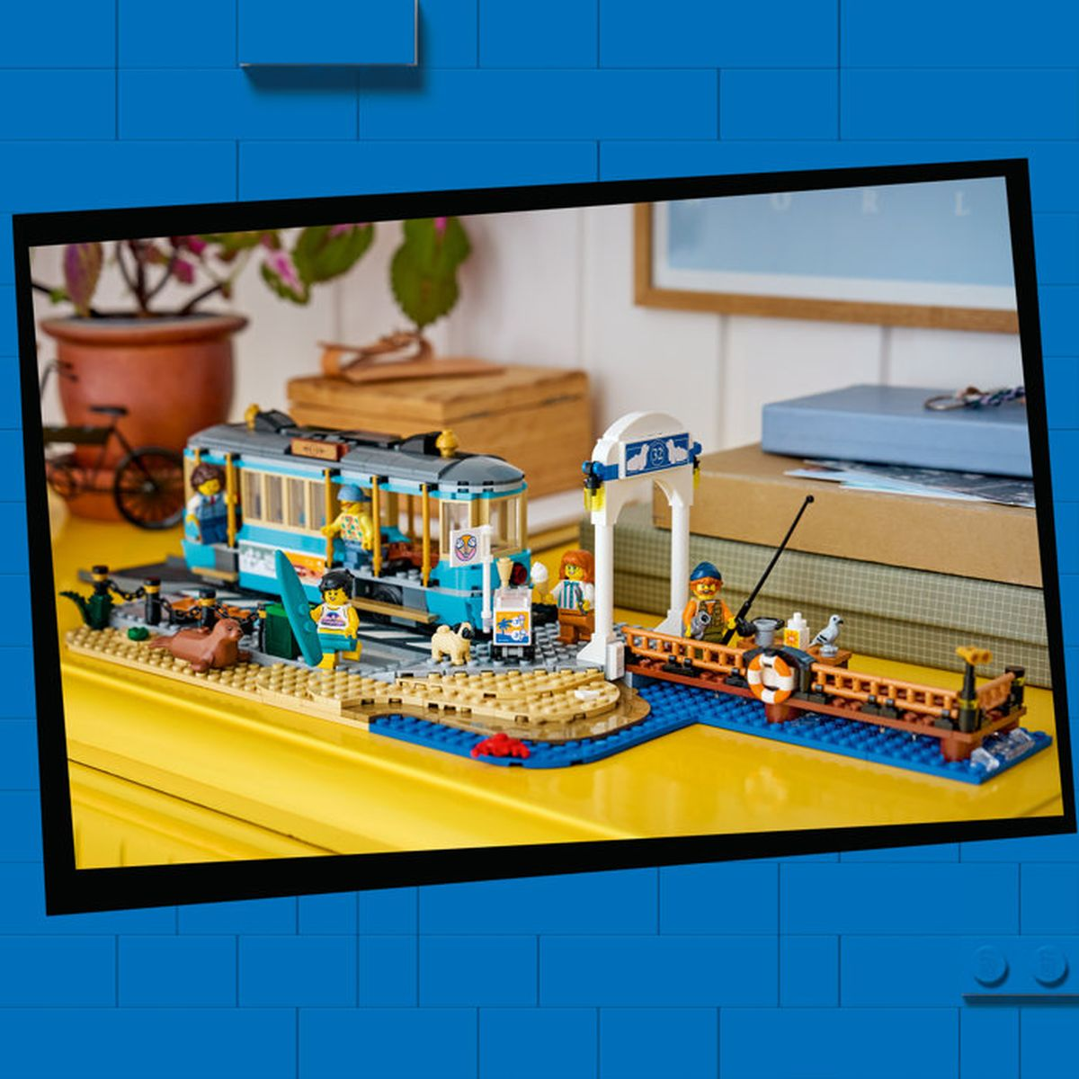 Una escena de Lego con un tranvía azul, muelle, figuras, animales y una bicicleta pequeña.