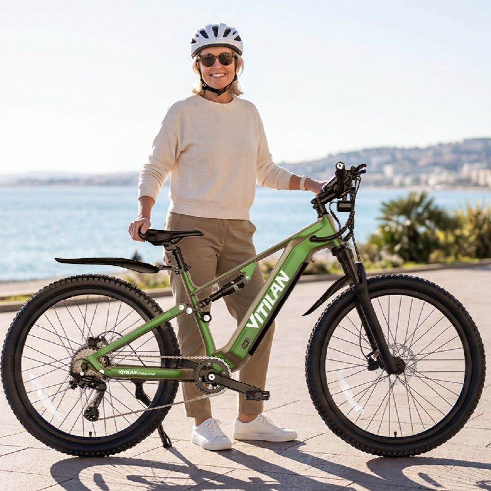 Una donna con casco e occhiali da sole sta vicino a una e-bike verde vicino al mare.