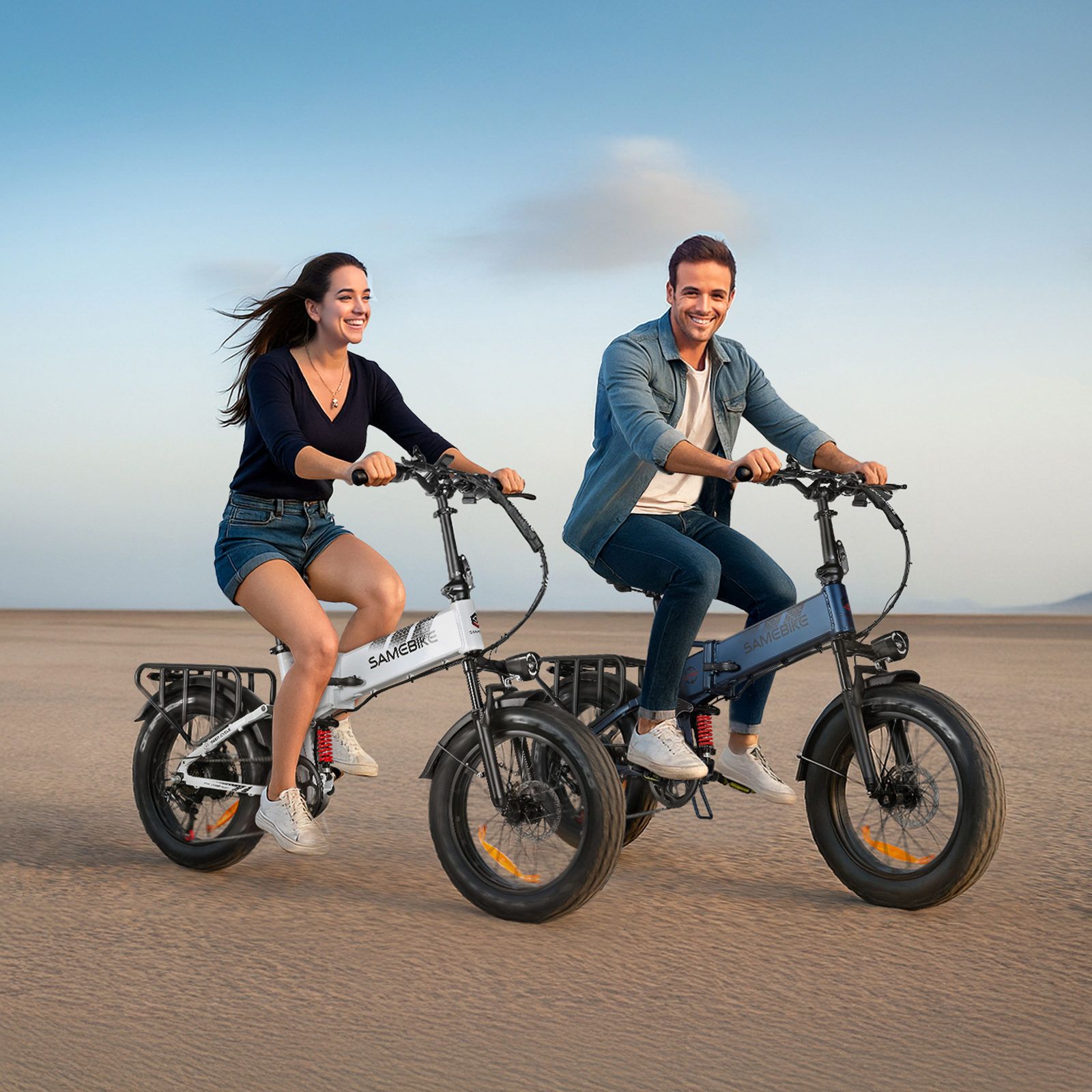 Una pareja monta en bicicletas eléctricas por una llanura arenosa bajo un cielo azul.