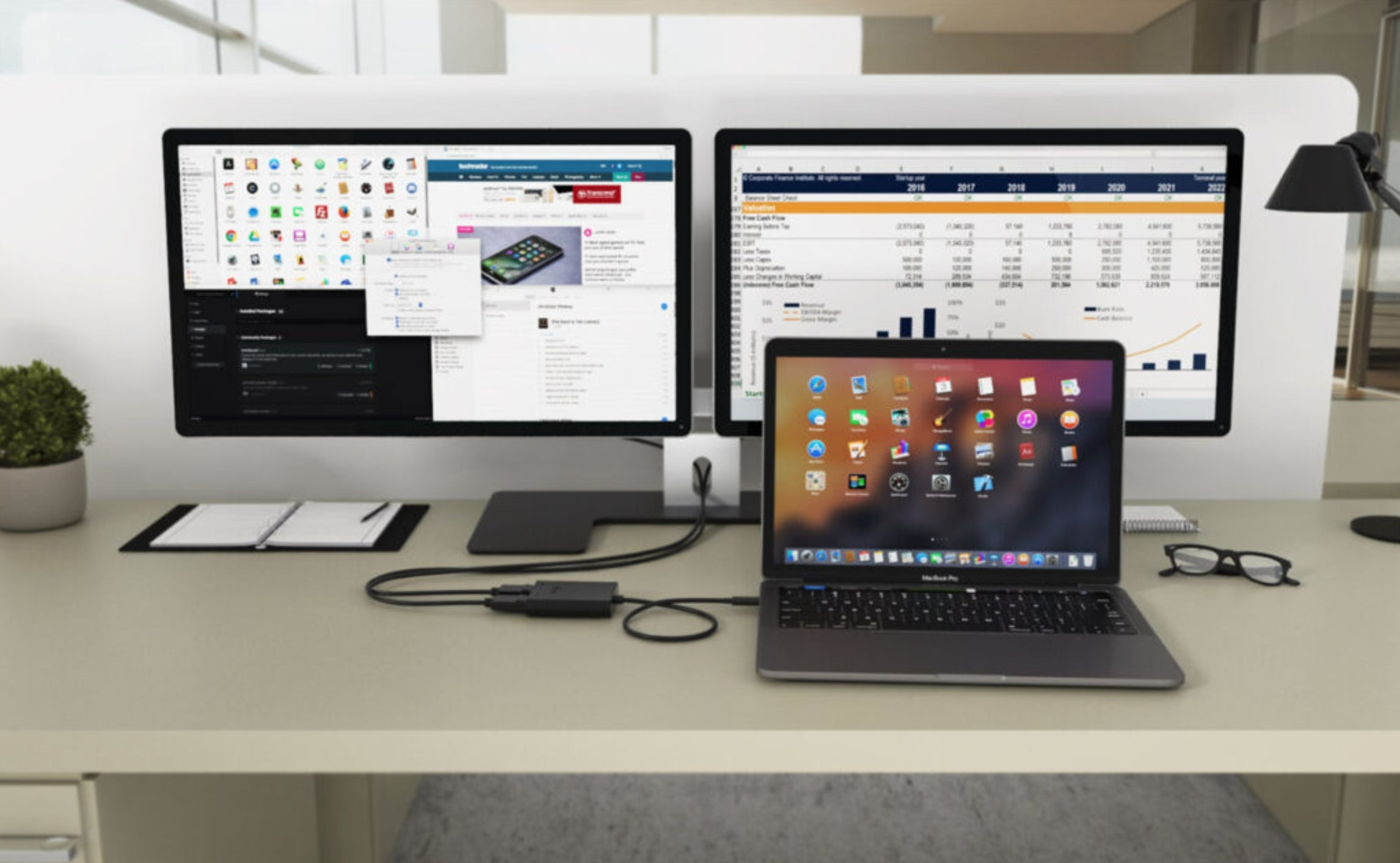 Scrivania con due monitor, un laptop e accessori.