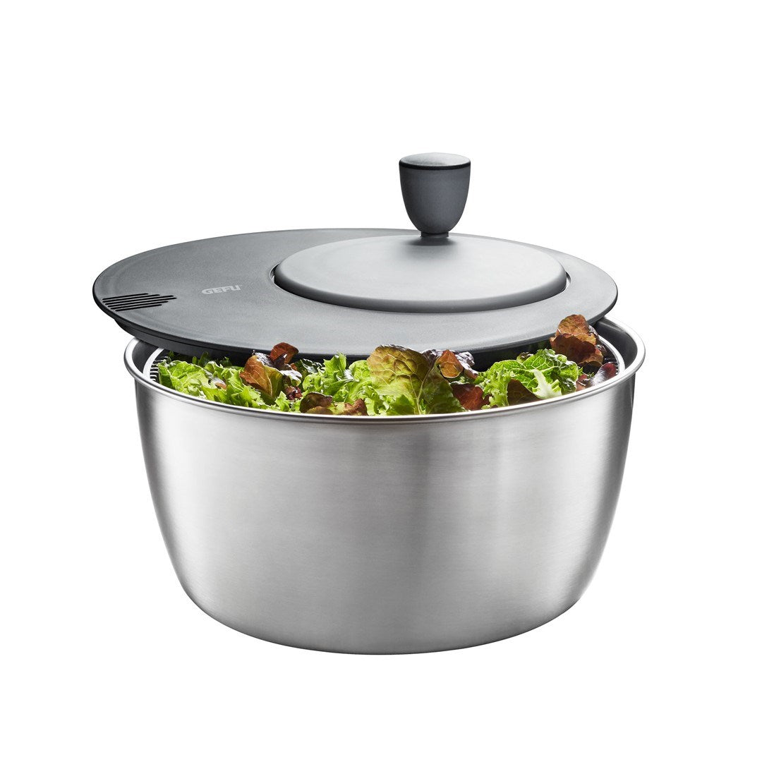 Eine Salatschleuder aus Edelstahl mit grauem Deckel und Griff, gefüllt mit grünem Salat.