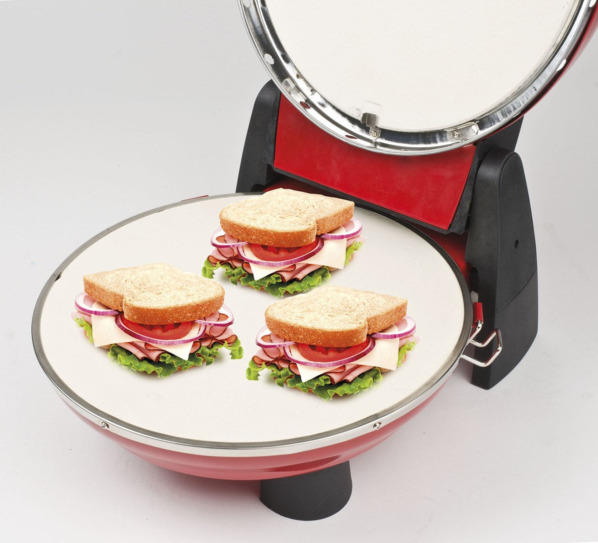 Tres sándwiches con pan tostado, lechuga, tomate, cebolla y jamón en una sandwichera.