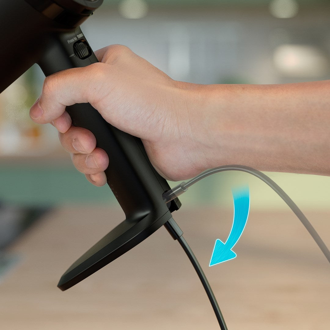 Eine Hand hält ein schwarzes Gerät, während ein Kabel angeschlossen wird.