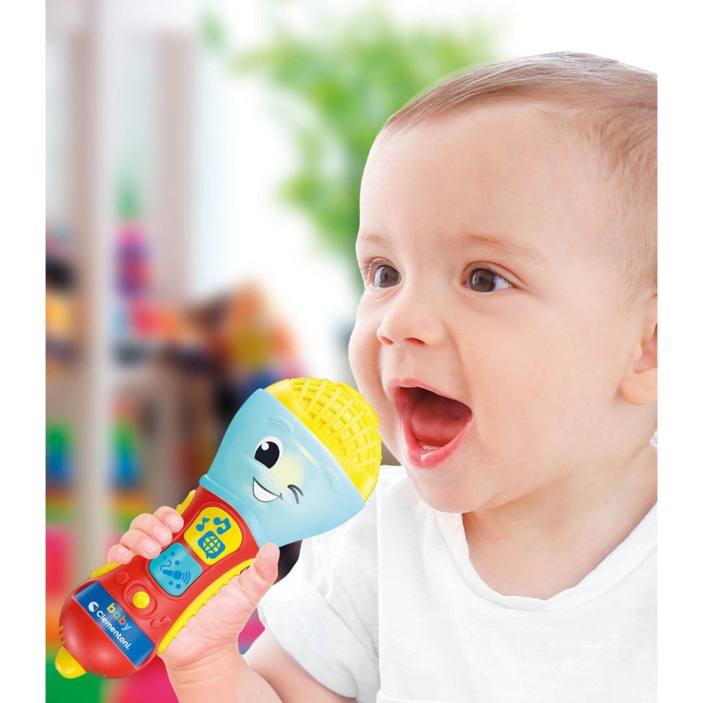 Un bambino in camicia bianca tiene in mano un microfono giocattolo colorato.