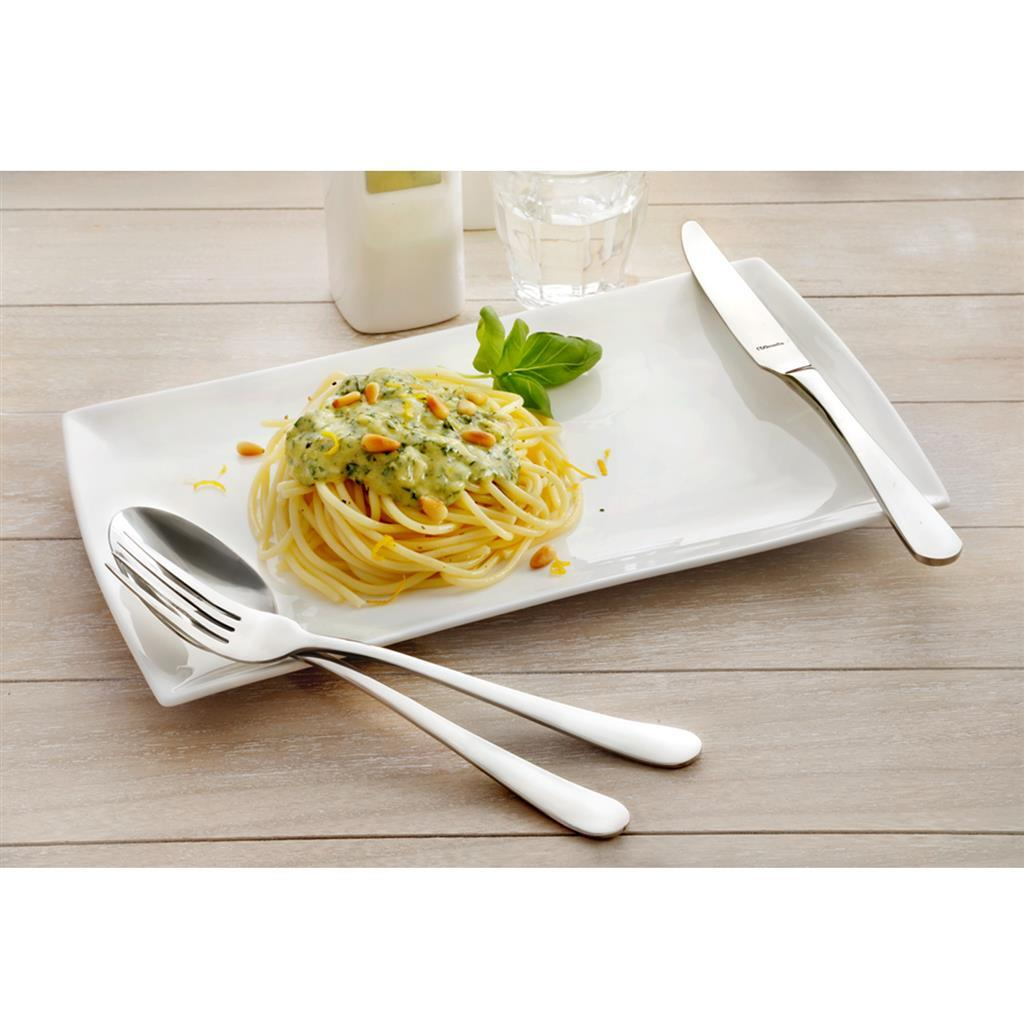 Spaghetti mit Kräutersoße und Pinienkernen auf einem weißen Teller mit Besteck.