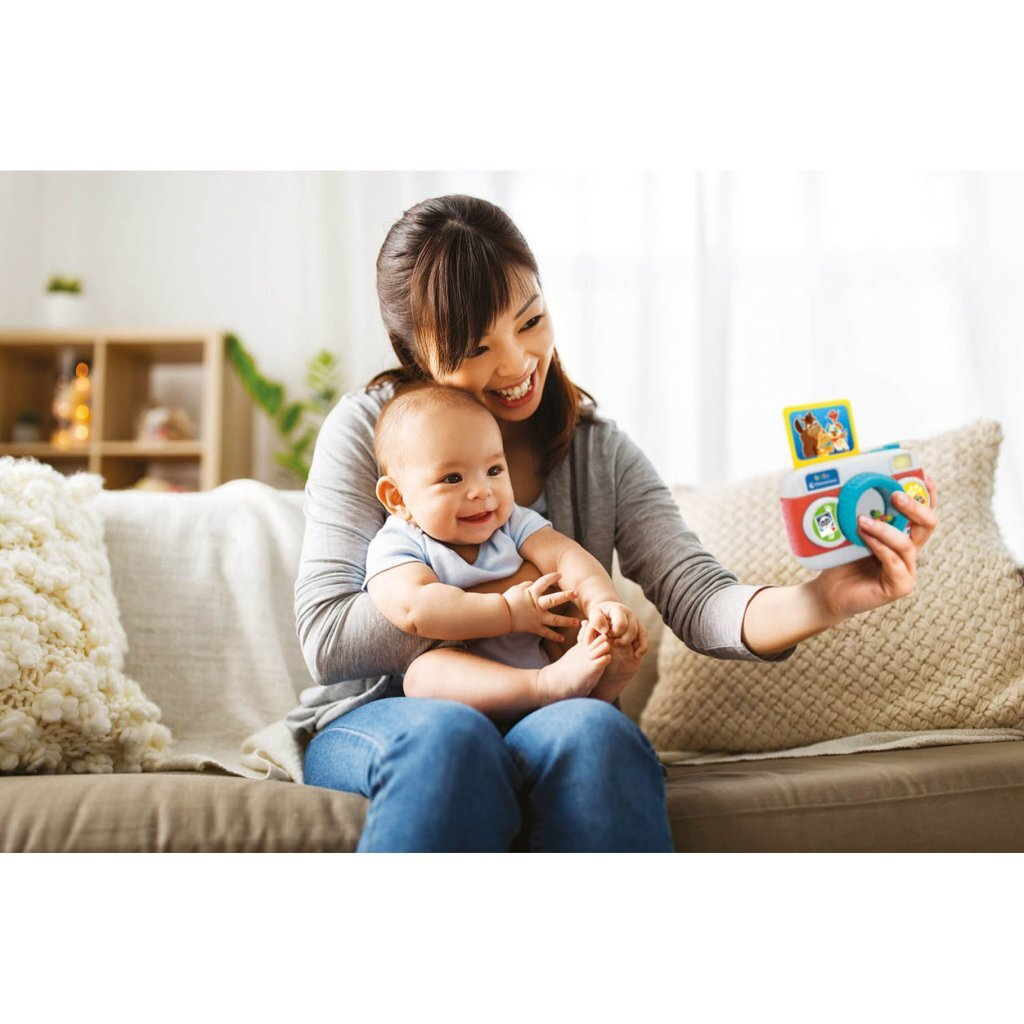 Una donna tiene un bambino e scatta una foto con una macchina fotografica giocattolo.