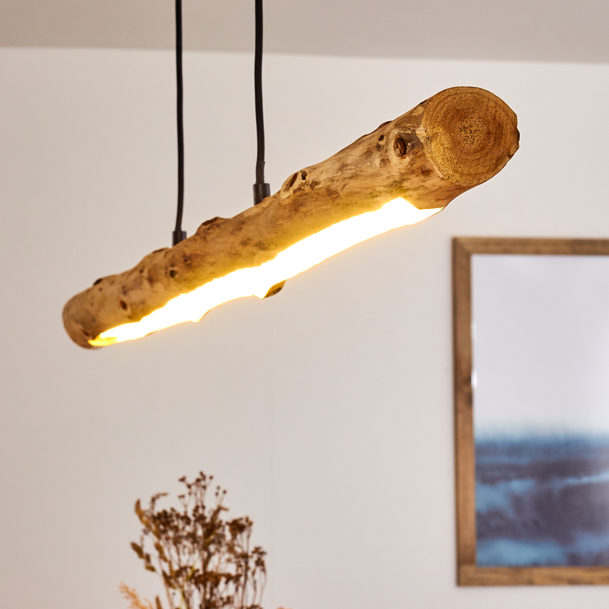 Eine rustikale Holzscheit-Leuchte mit warmem gelbem Licht, die an schwarzen Kabeln hängt.