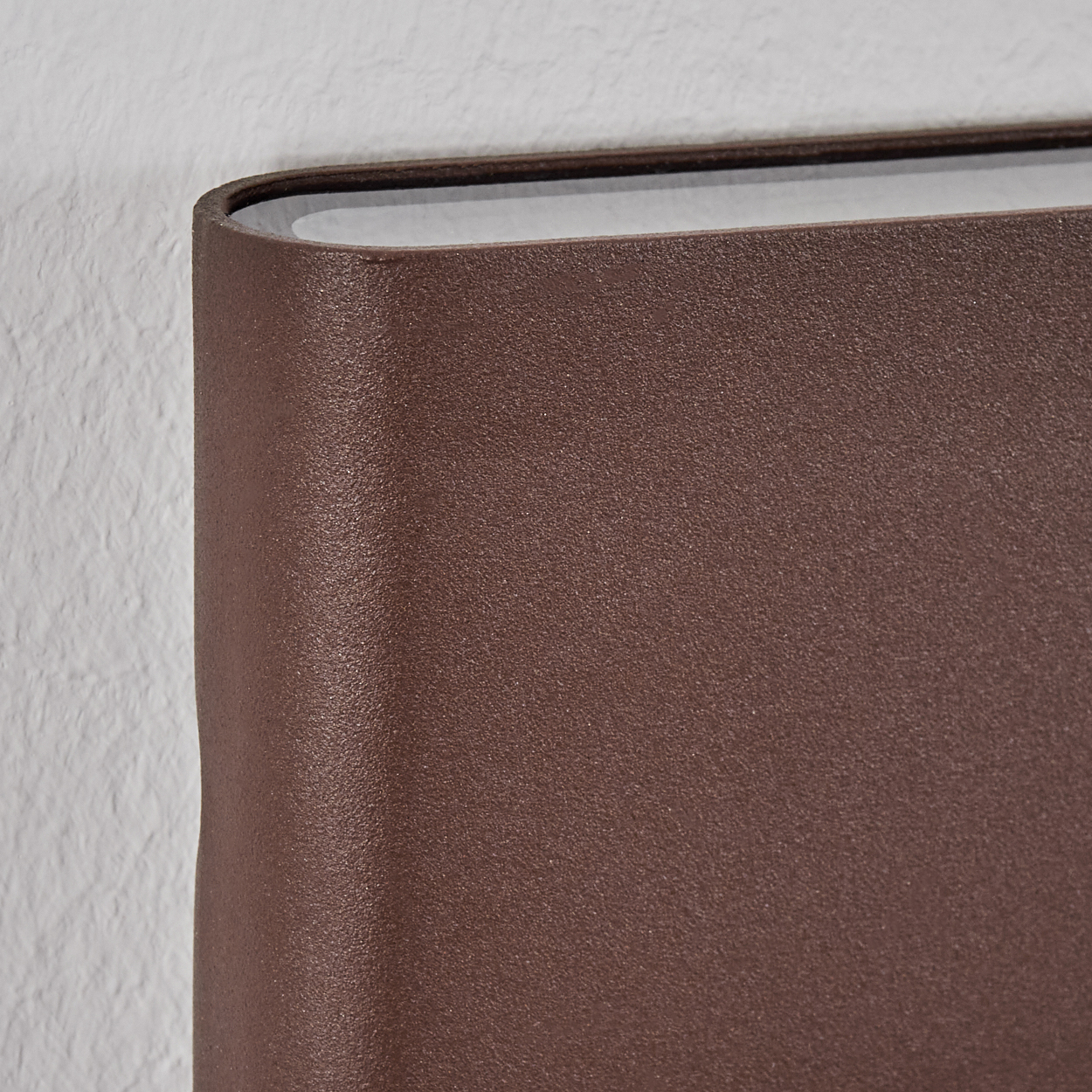 Brauner Buchrücken neben einer weißen Wand.