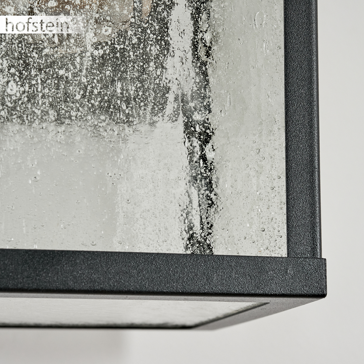 Nahaufnahme einer schwarzen Lampe mit strukturiertem Glas und Wassertropfen.