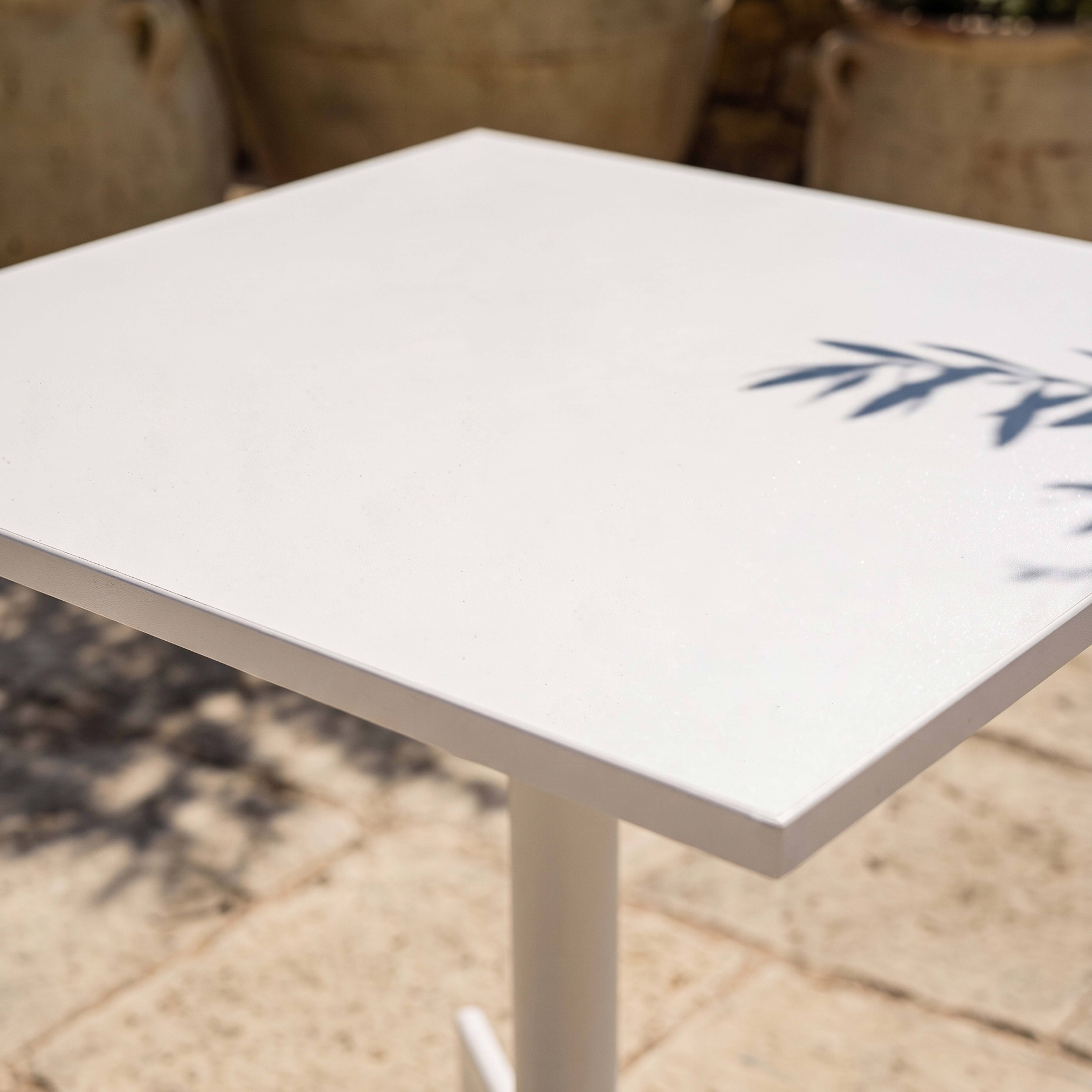 Ein weißer Tisch mit Schatten von Zweigen im Freien.