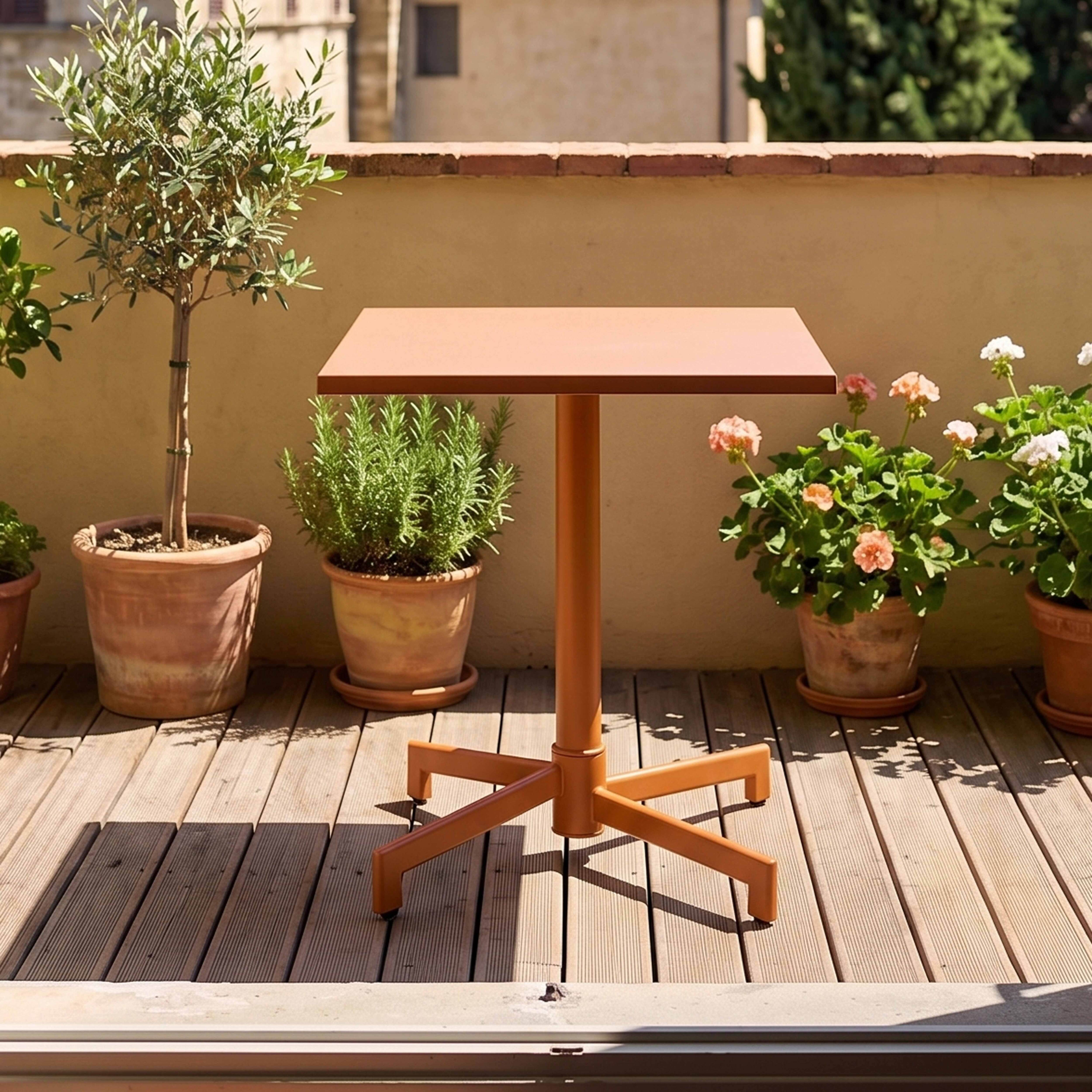 Ein orangefarner Tisch mit mehreren Pflanzen auf einer Holzterrasse.