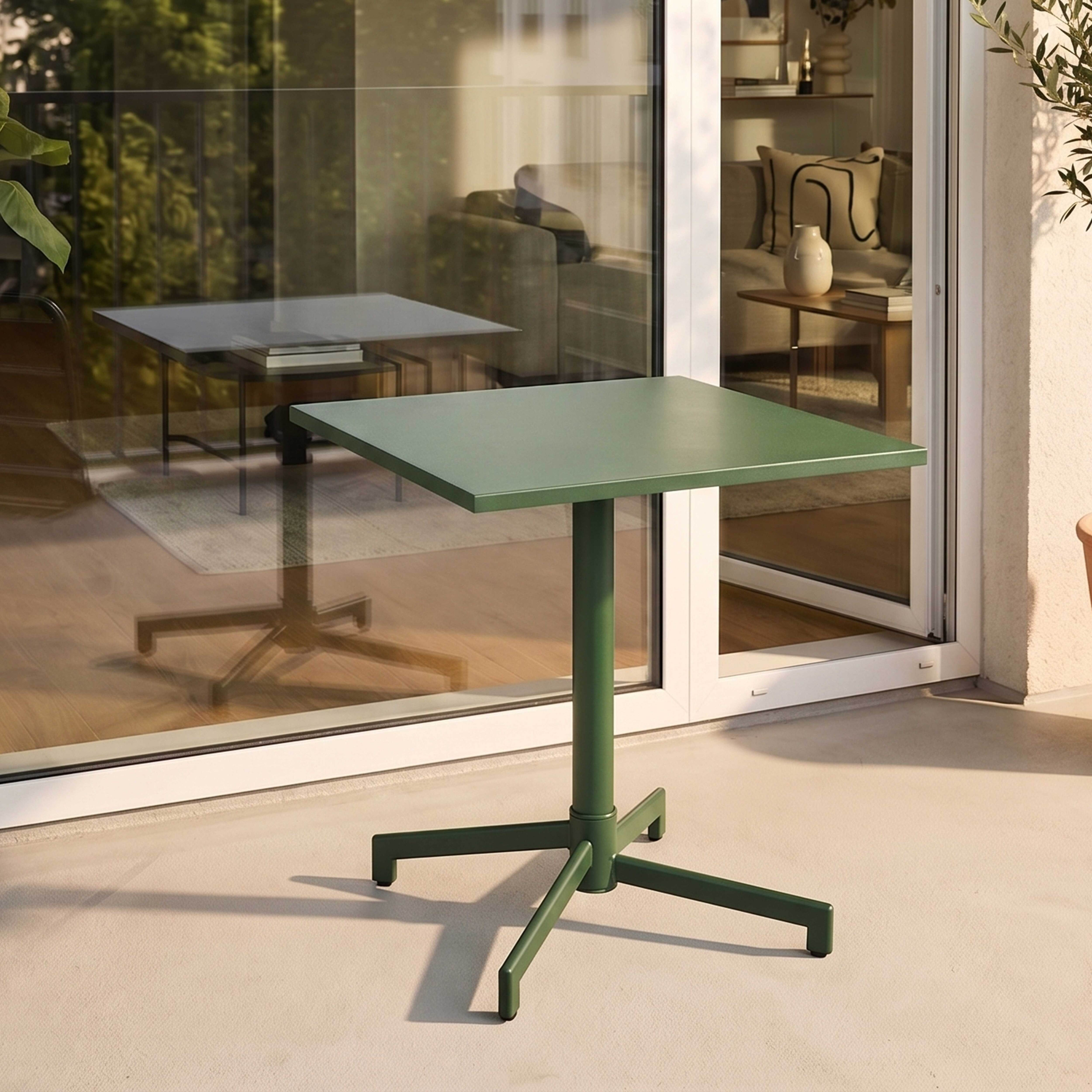 Ein grüner quadratischer Tisch mit einem einzelnen Fuß steht auf einer Terrasse.