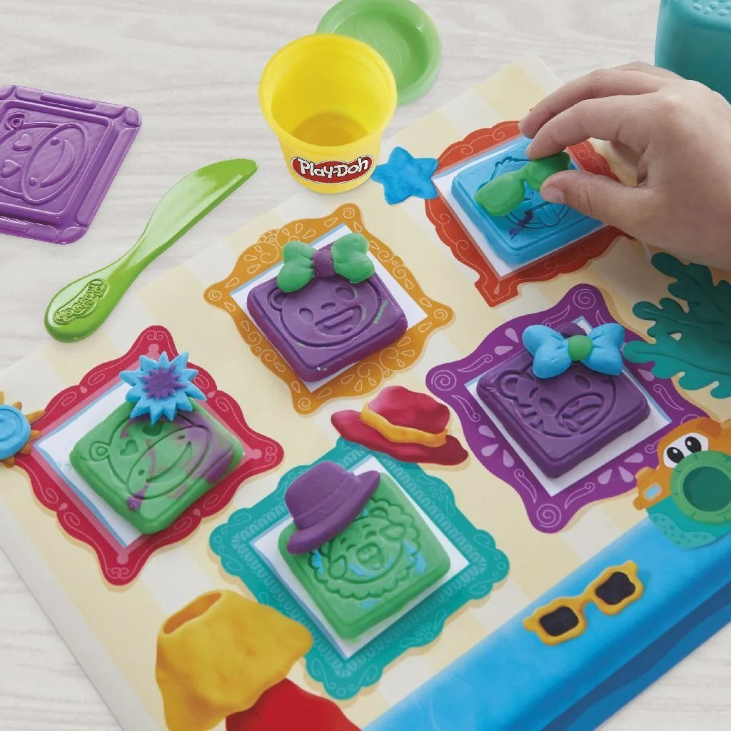 Moldes de Play-Doh con caras, sombreros y lazos en una tabla.