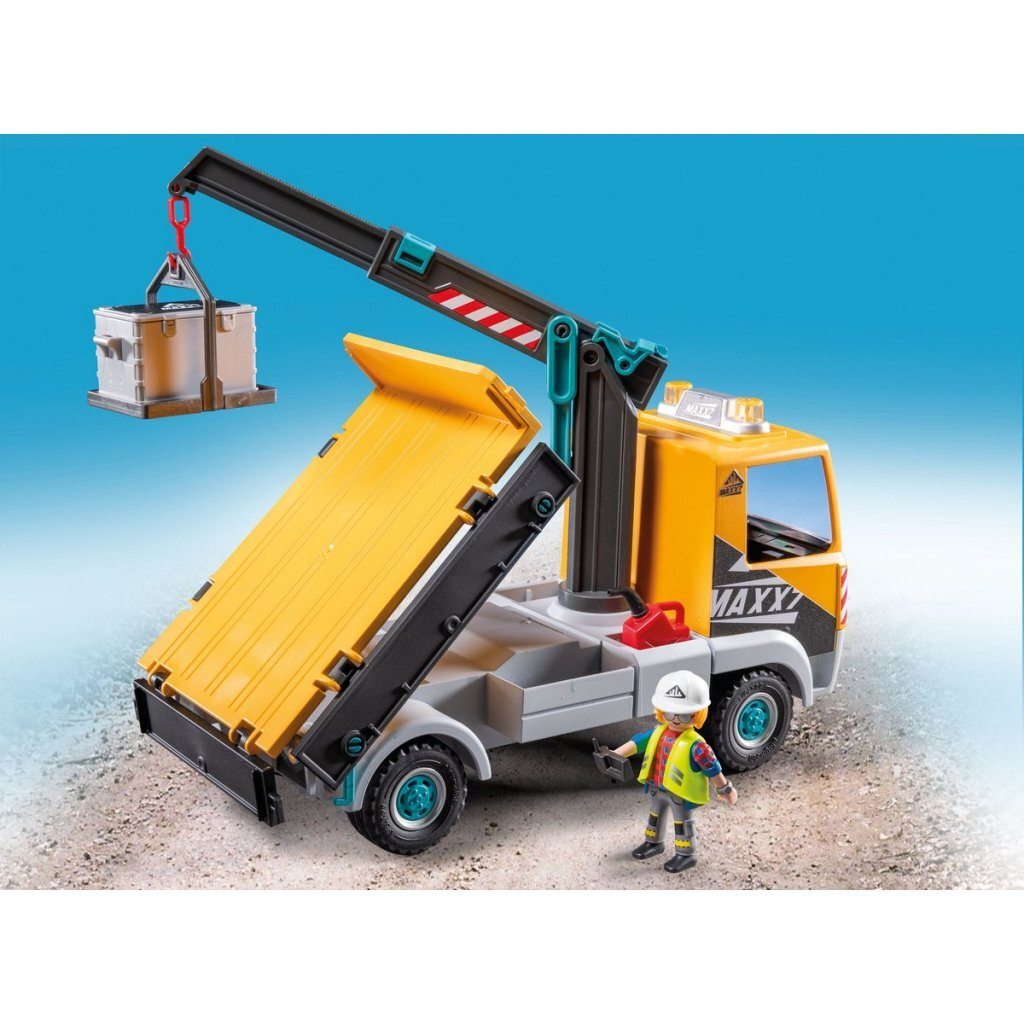 Camion gru giallo con container sollevato e figura giocattolo.