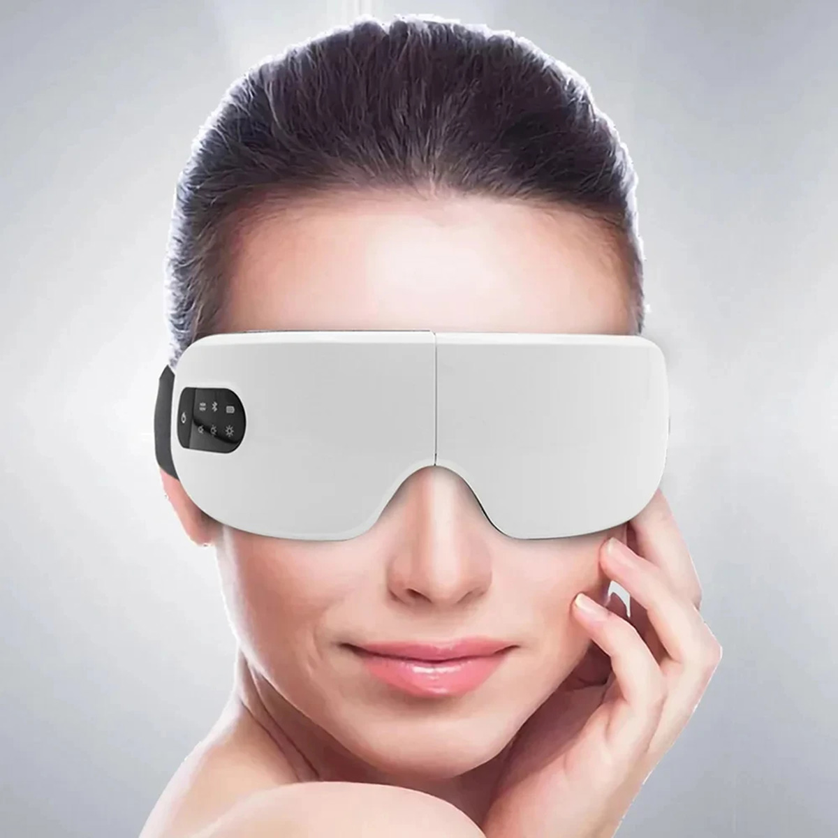 Una mujer con una máscara de masaje ocular blanca con botones de control.
