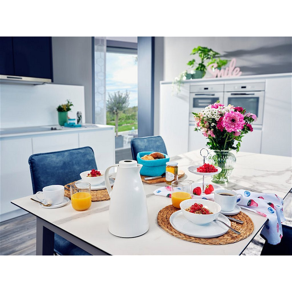 Ein gedeckter Tisch mit Frühstück, Blumen und Kaffee.