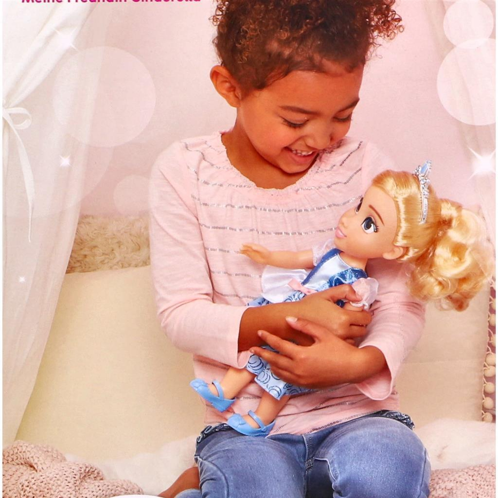 Una niña sostiene una muñeca de princesa con un vestido azul.