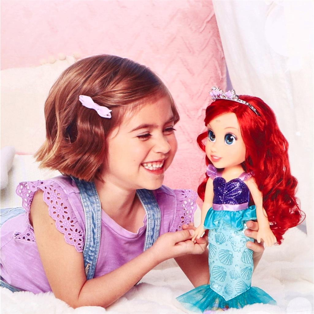 Una niña de pelo castaño juega con una muñeca de Ariel con top morado.
