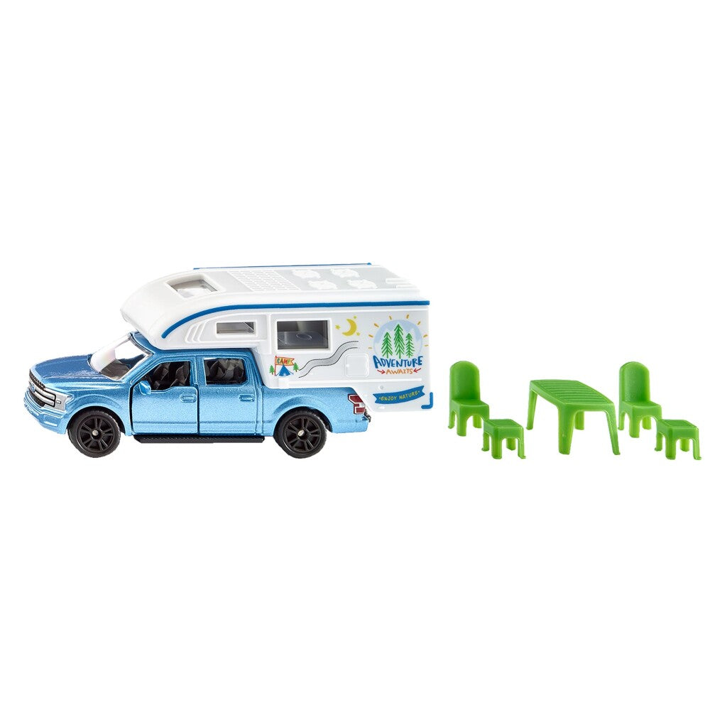 Ein blaues Wohnmobil Spielzeug neben einem grünen Tisch und vier Stühlen.