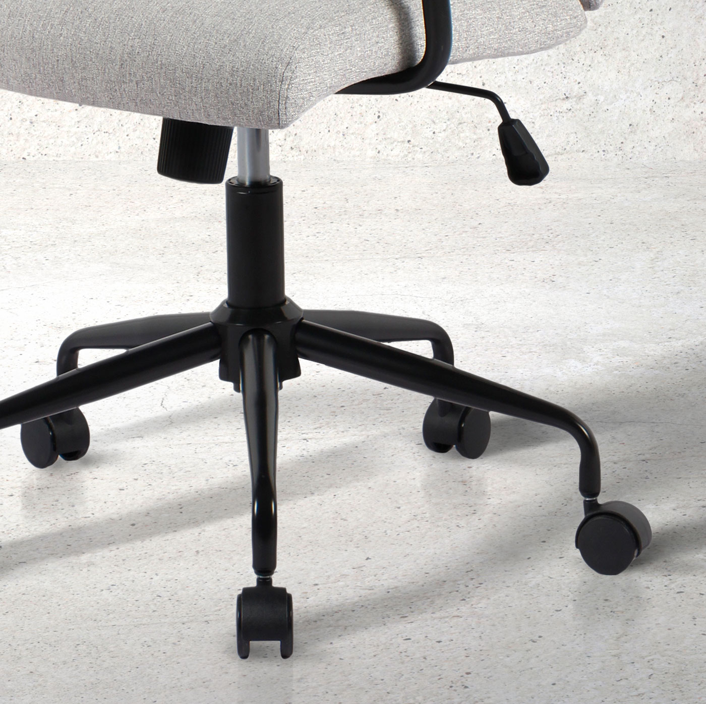 Silla de oficina con asiento gris y base negra con ruedas sobre suelo de hormigón.