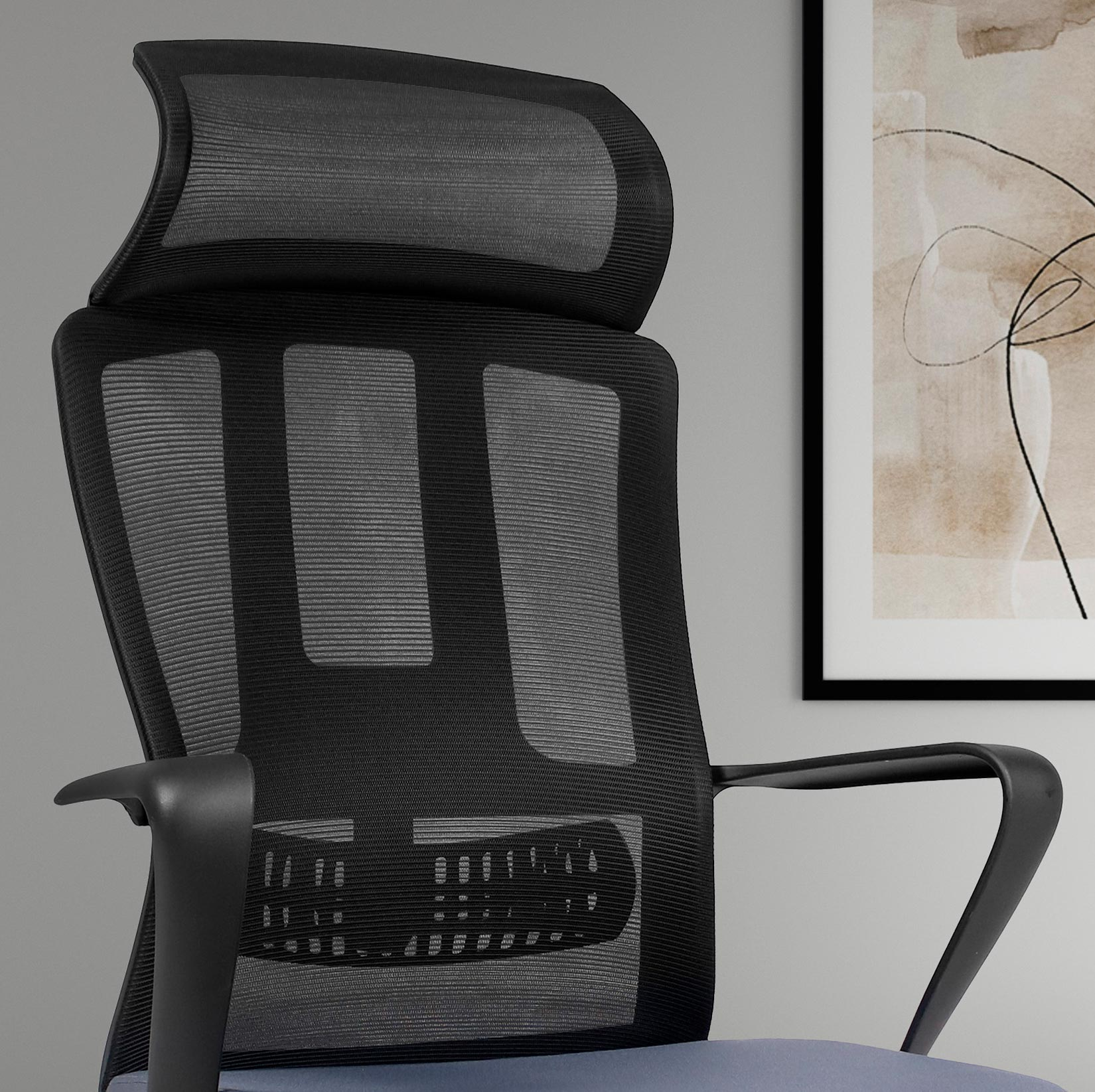 Silla de oficina de malla negra con reposacabezas y un cuadro.