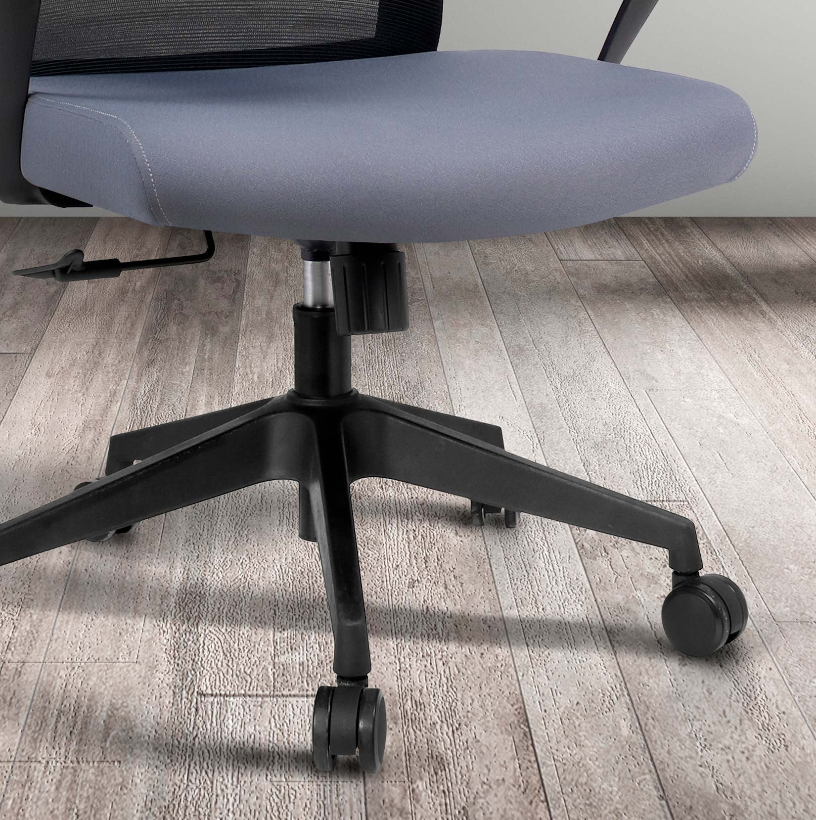 Silla de oficina gris con base negra y ruedas sobre suelo de madera.