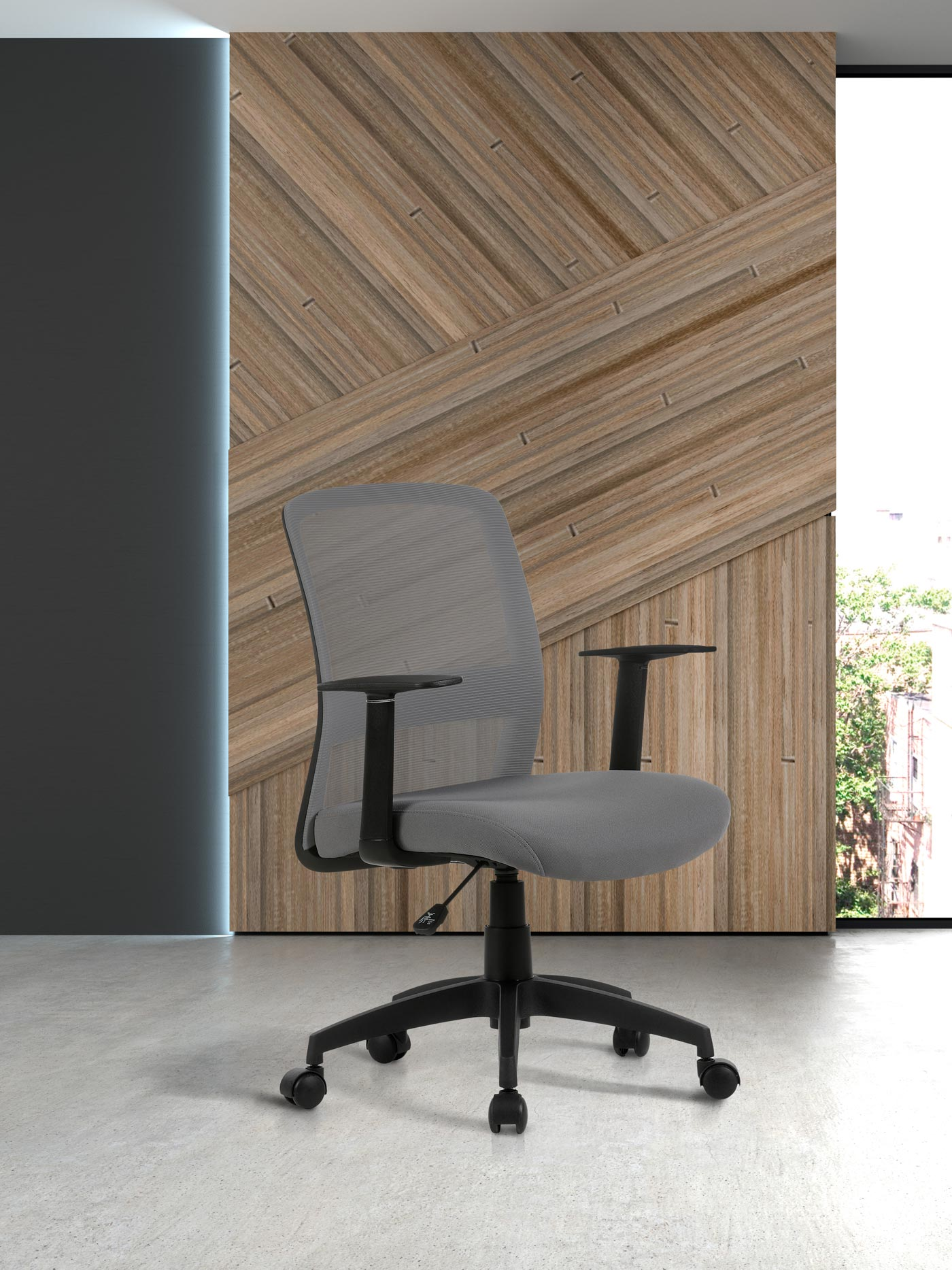 Silla de oficina gris con respaldo de malla y reposabrazos en suelo de hormigón.