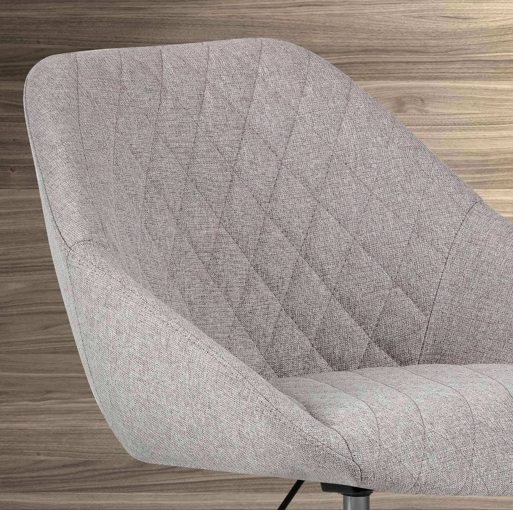 Silla de tela gris con acolchado de rombos y fondo de madera.